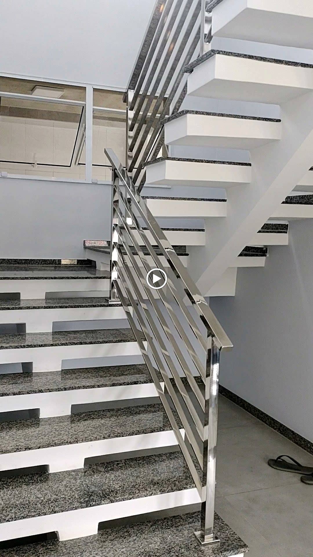Escada de degraus em balanço e granito com guarda-corpo em tubo quadrado de inox polido